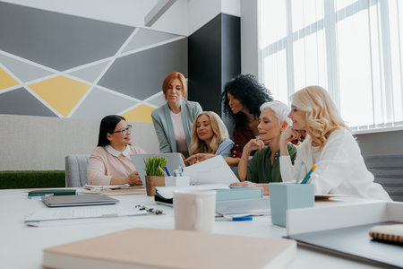 Group of mature women looking at laptop while discussing business in the office togetherの写真素材