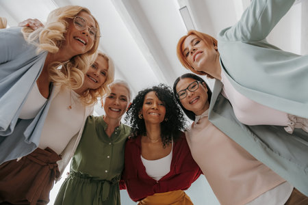 Low angle view of group of confident mature women embracing and smiling at camera