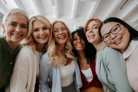 Low angle view of multi-ethnic group of mature women embracing and smiling at cameraの写真素材