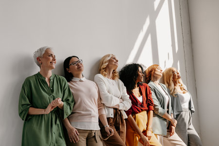 Multi-ethnic group of mature women bonding and smiling while leaning on the wall togetherの写真素材