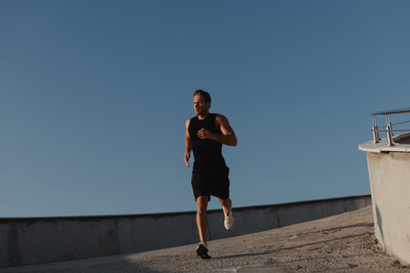 Handsome young man in sports clothing enjoying morning jog outdoors