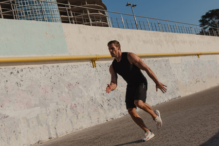 Full length of confident young male athlete in sports clothing running outdoors