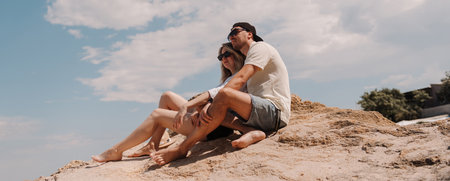 Beautiful romantic couple bonding while enjoying the scenery on the top of rocky mountain togetherの写真素材