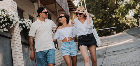 Three happy young friends embracing and smiling while walking by the street togetherの写真素材