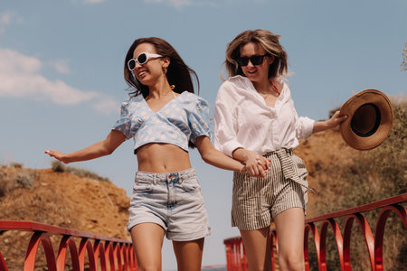 Two happy young women holding hands and smiling while running outdoors togetherの写真素材