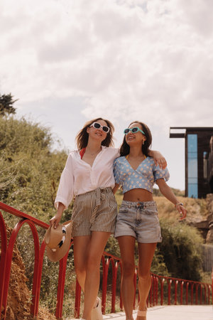 Two happy young women embracing and smiling while walking outdoors togetherの写真素材
