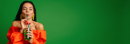 Attractive young woman enjoying fresh lemonade and keeping eyes closed against green background