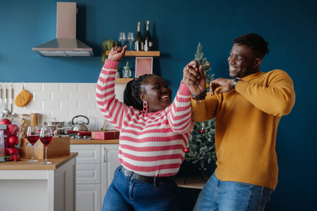 Happy young African couple dancing and smiling while celebrating New Year at home togetherの写真素材