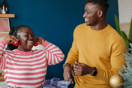 Joyful young African couple having fun while decorating Christmas tree at home together