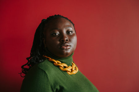 Portrait of beautiful plus size African woman looking at camera on red backgroundの写真素材