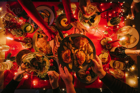 Top view of people enjoying variety of Christmas dishes while having holiday dinner at the tableの写真素材