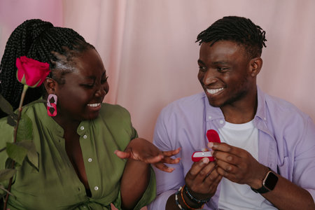 Romantic African man giving engagement ring to his girlfriend while making proposalの写真素材