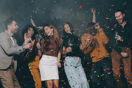 Group of smiling young people enjoying New Year party in the night club with confetti flying aroundの写真素材