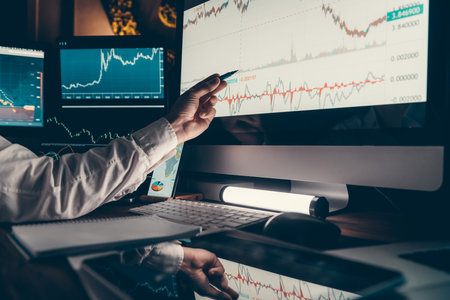 Close-up of male trader pointing computer monitor while analyzing stock market charts in officeの写真素材