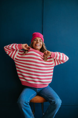 Playful young blond hair woman showing her new trendy sweater and smiling on blue backgroundの写真素材