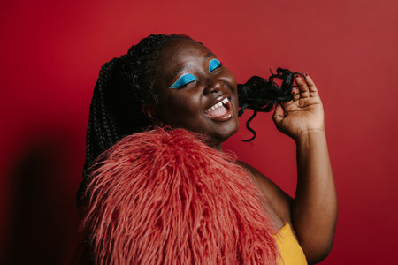 Fashionable plus size African woman with beautiful make-up touching hair and smilingの写真素材