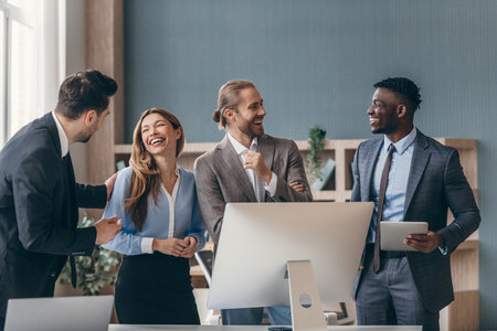Confident business team looking happy while standing near the computer monitor in office togetherの写真素材