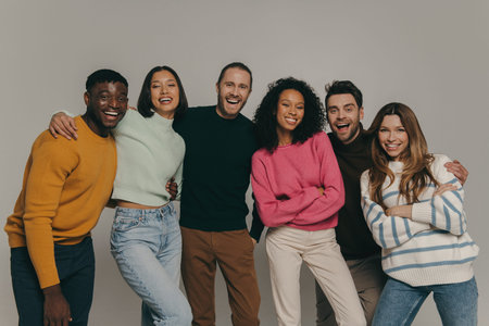 Joyful young people bonding and smiling while standing on beige background togetherの写真素材