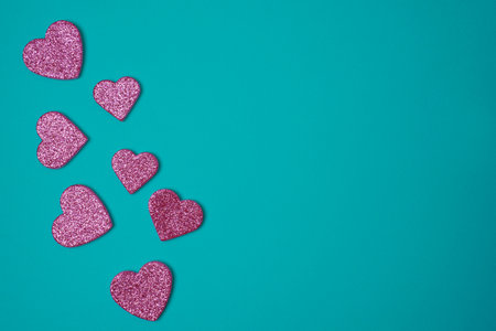 Glittering pink hearts on blue green turquoise background. Valentines day concept. copyspace. flat lay.の写真素材