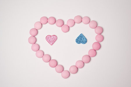 Sweets candies as heart with pink and blue glittering hearts on white background. Valentines day concept. flat lay.の写真素材
