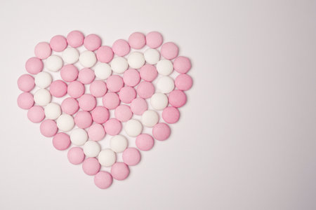 Sweets white and pink candies as heart on white background. Valentines day concept. women's day. flat lay. copyspace.の写真素材