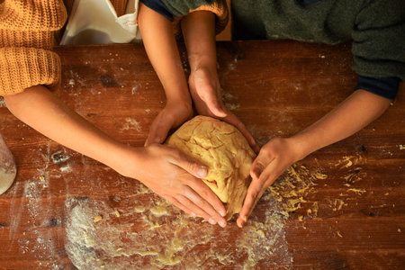 Children kneading cookie dough with their hands on a wooden table.の写真素材