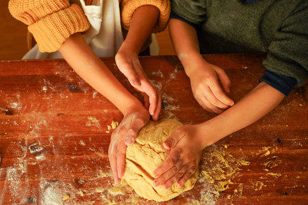 Hands of children kneading cookie dough with their hands on a wooden table.の写真素材