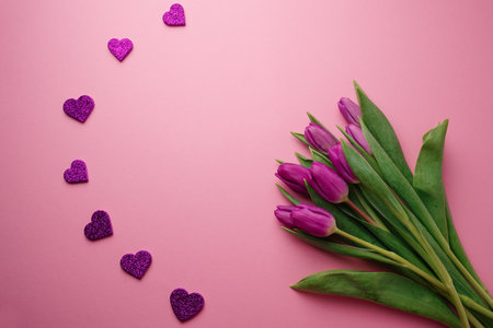 Bouquet of purple tulips with hearts on rose background. Mothers day, Valentines Day, Birthday celebration concept. greeting card. Copy space, top view.の写真素材