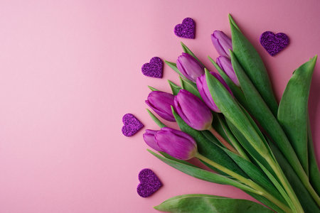 Bouquet of purple tulips with hearts on rose background. Mothers day, Valentines Day, Birthday celebration concept. greeting card. Copy space, top view.の写真素材