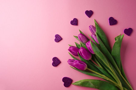 Bouquet of purple tulips with hearts on rose background. Mothers day, Valentines Day, Birthday celebration concept. greeting card. Copy space, top view.の写真素材