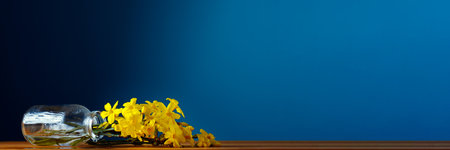 Yellow flowers in fallen bottle with water on blue background. The minimal concept. copyspace.の写真素材