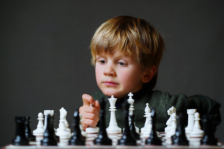 Concentrated child developing chess strategy, playing board game with friend, cute little boy playing chess.の写真素材