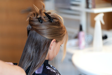 Hair stylist makes young girl hairstyle. Long light brown natural hair.の写真素材