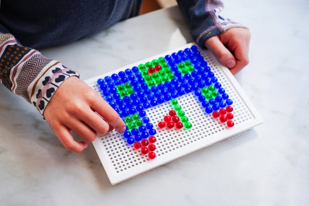 Little child building a castle from mushroom nail mosaic. Playing with puzzle for preschoolers for developing creativity and motor skills. early education. Hobby and leisure time.の写真素材