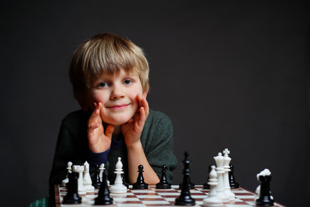 Portrait of cute blond child with chess, playing board game, little boy playing chessの写真素材