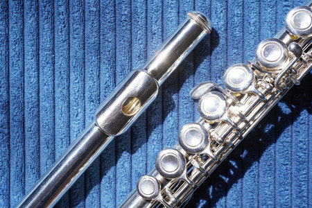 Close-up of silver flute, with detailed view of the mouthpiece, shiny surface and keys of the...
