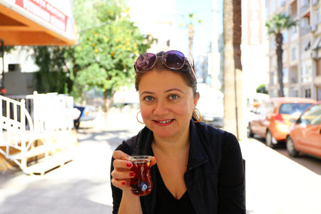 Middle aged blonde female holds cup of tea to drink.の写真素材