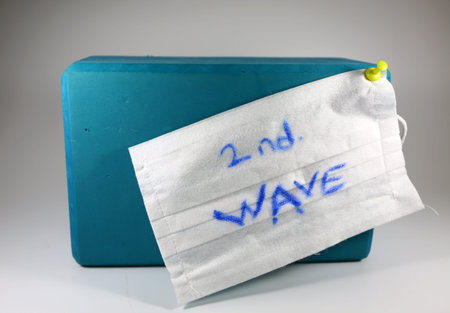 Blue colored yoga block and covid-19 second wave warning mask shot together.の写真素材