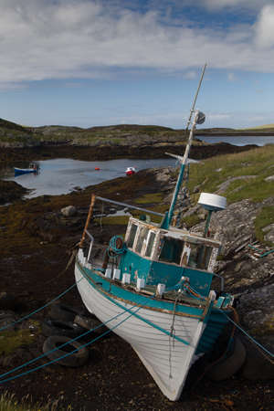 Old fishing boat on the rocks with the tide out on the Isle of Barra in the Outer Hebridesの写真素材