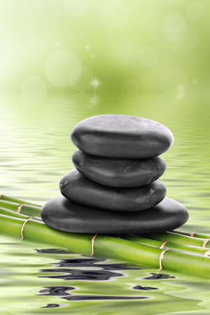 Zen basalt stones on bamboo on waterの写真素材