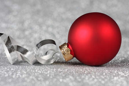Red Christmas ornament with curled ribbon on a silver backgroundの写真素材