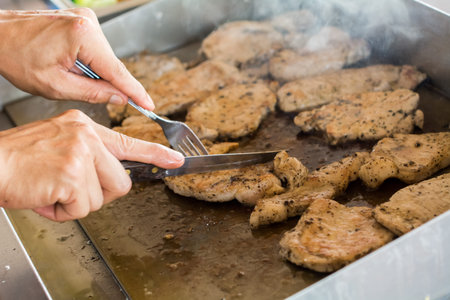 roasting meat with oil or butter in saucepan in interior of modern restaurant kitchen