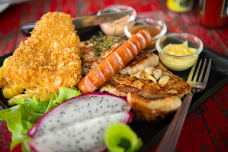 top view of mix steak with and fresh green herb salad and dragon fruit on vintage wooden tableの写真素材