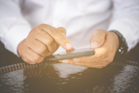 Closeup view of male hands touching mobile phone.