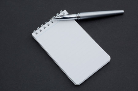 small notepad and pen isolated on a dark background