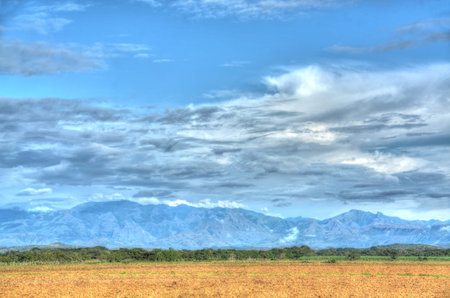 Plowed field with a beautiful blue sky and mountains in the background in the countryside of Panamaの写真素材