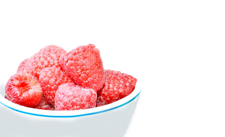Bowl with fresh raspberries on white with copy space