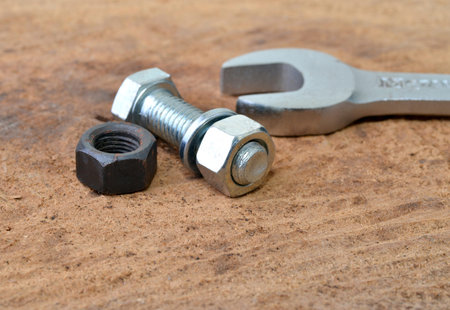 Macro shot of bolt, nuts and a wrench on a table