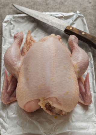 AI-generated image that shows a raw whole chicken placed on a sheet of foil, ready for preparation.の素材