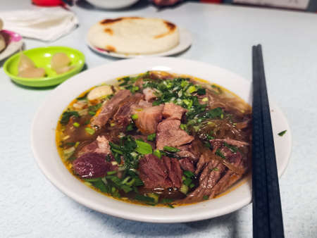Beef noodle soup in a white plate on the table.の写真素材